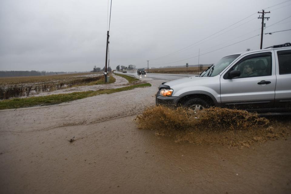 A woman in vehicle turns onto State Road in Eagle Township where heavy rains have flooded part of the road, Wednesday, April 5, 2023.