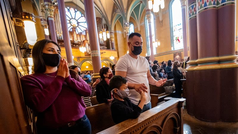 Guadalupe Navarro, left, Ivan Trejo, and father Ivan Trejo attend a special reading of the Gospel and blessing of palm branches for Palm Sunday at the Cathedral Madeleine in Salt Lake City on Sunday, March 28, 2021.