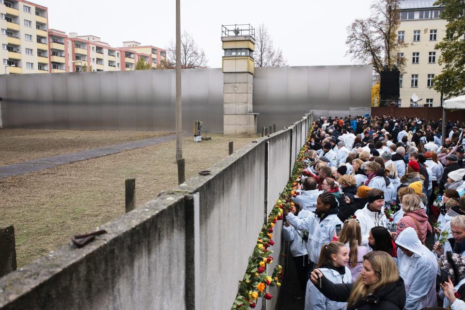 People stuck flowers in remains of the Berlin Wall during a commemoration ceremony to celebrate the 30th anniversary of the fall of the Berlin Wall at the Wall memorial site at Bernauer Strasse in Berlin, Saturday, Nov. 9, 2019.