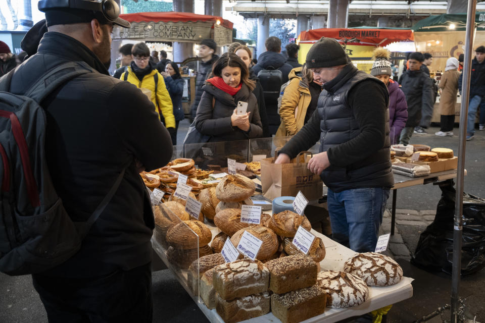 Inflation. Market trader serves customers at his bread stall at Borough Market on January 16, 2024 in London, United Kingdom. Borough Market is a retail food market and farmers' market in Southwark. It is one of the largest and oldest food markets in London, with a market at this location dating back to at least the 12th century. A farmers' market is a physical retail market designed to sell food directly from farmers to consumers. (Photo by Mike Kemp/In Pictures via Getty Images)