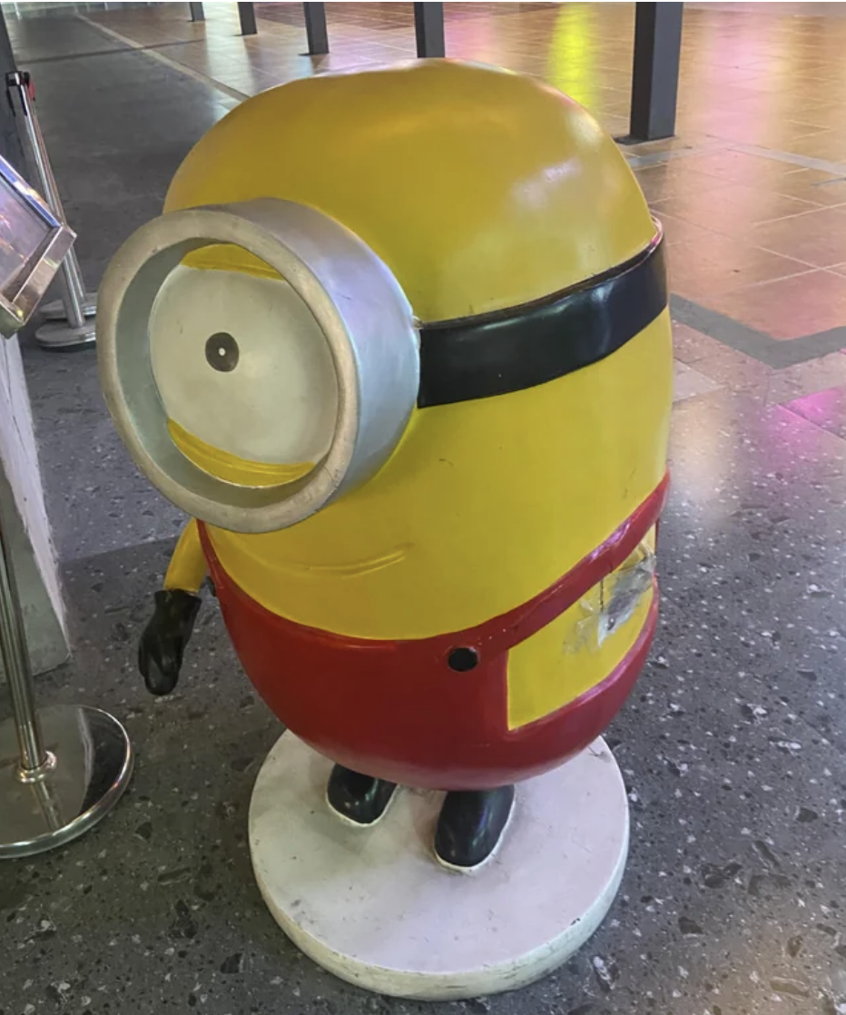 A Minion statue from the move "The Minions" with a pained smile and a missing arm