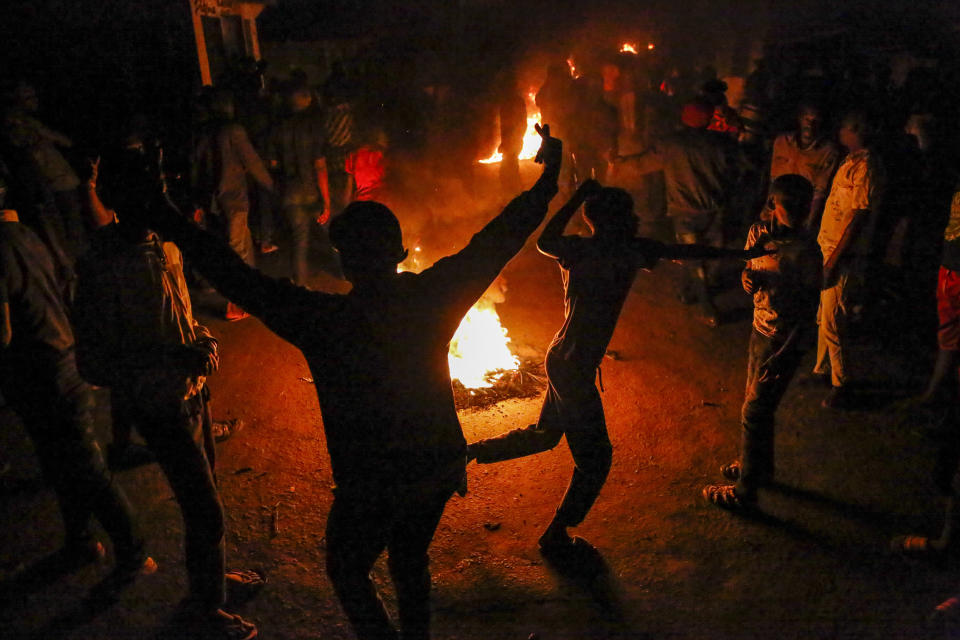 In this photo taken Monday, June 1, 2020, residents burn fires late at night on a street to protest the death of James Mureithi, a homeless man who protesters alleged was shot dead by police during the nightly dusk-to-dawn curfew established to curb the spread of the coronavirus, in the Mathare slum, or informal settlement, of Nairobi, Kenya. Hundreds of people in Mathare left their homes and burnt tires on the streets in the latest outrage over alleged police brutality, with a rights activist claiming that 19 Kenyans from low-income neighborhood have died from police actions in enforcing the curfew. (AP Photo/Brian Inganga)