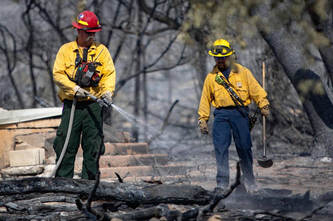 Firefighters spray water on the remains of a smoldering structure on Possum Kingdom Lake in Graford, Texas, on Wednesday, July 20, 2022.