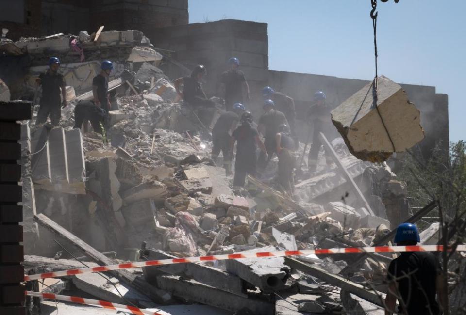 Ukrainian  firefighters clear debris at a damaged residential building 