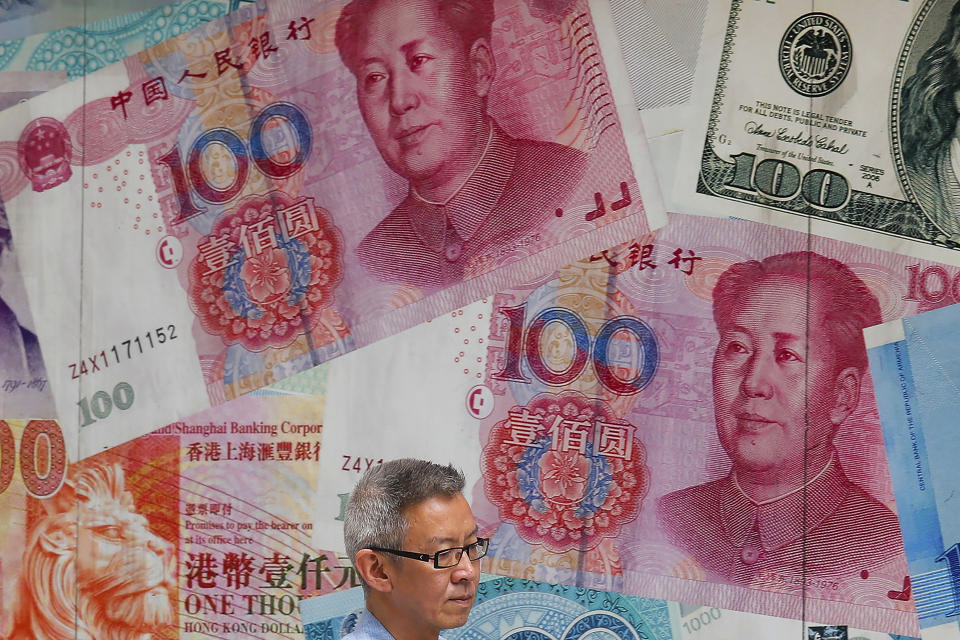 In this Tuesday, Aug. 6, 2019, photo, a man walks by a money exchange shop decorated with Chinese yuan banknotes and other countries currency banknotes at Central, a business district in Hong Kong. China's yuan has weakened again after signs its decline was stabilizing helped to reassure financial markets. (AP Photo/Kin Cheung)