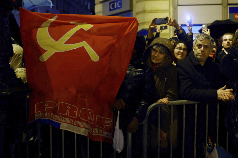 People hold a Party Communist flag as they gather during Missak Manouchian's induction ceremony and his 23 resistance fighters into the Pantheon monument, Wednesday, Feb 21, 2024 in Paris. A poet who took refuge in France after surviving the Armenian genocide, Manouchian was executed in 1944 for leading the resistance to Nazi occupation. (Sarah Meyssonnier/Pool via AP)