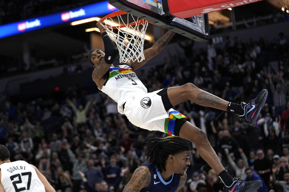 Minnesota Timberwolves forward Jaden McDaniels (3) dunks against Memphis Grizzlies guard Ja Morant (12), bottom, during the second half of an NBA basketball game, Friday, Jan. 27, 2023, in Minneapolis. (AP Photo/Abbie Parr)