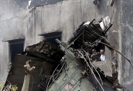 Security forces examine the wreckage of an Indonesian military C-130 Hercules transport plane after it crashed into a residential area in the North Sumatra city of Medan, Indonesia, June 30, 2015. REUTERS/Roni Bintang