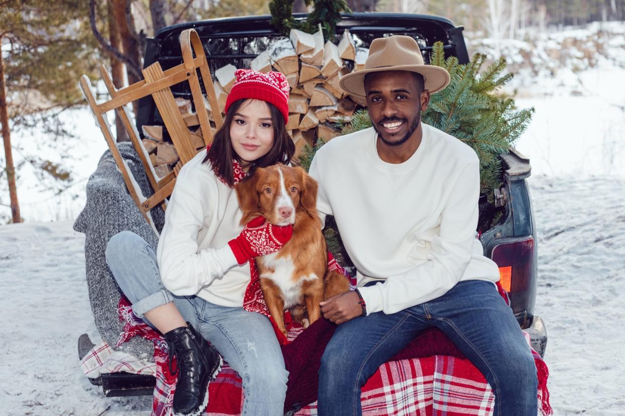 couple posing with their dog in a snowy, holiday scene for their Christmas card