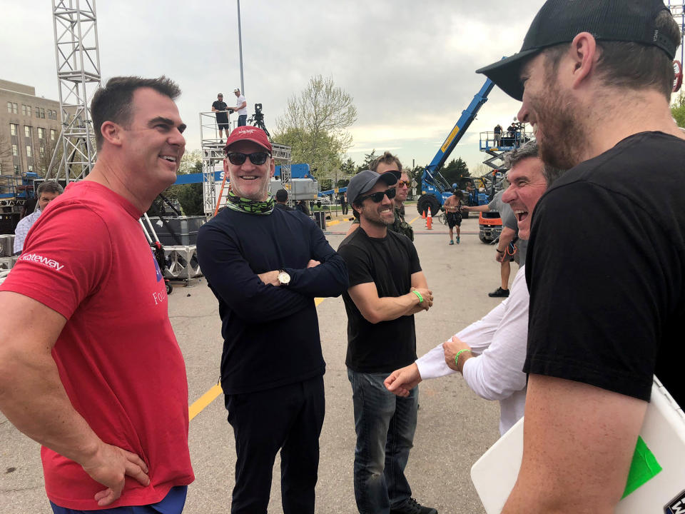 This Wednesday, April 10, 2019 photo Oklahoma's new Republican Gov. Kevin Stitt, left, talks on the set of "American Ninja Warrior" outside the state Capitol in Oklahoma City, Okal., after trying out the obstacle course. Organizers of the reality television show that features high-level athletes racing through grueling obstacles say the 47-year-old ex-CEO is the first governor to give the course a try. Stitt bloodied his elbow completing a rope swing to a landing pad after jumping across a pool of water. (Donelle Harder/Office of Governor Kevin Stitt via AP)