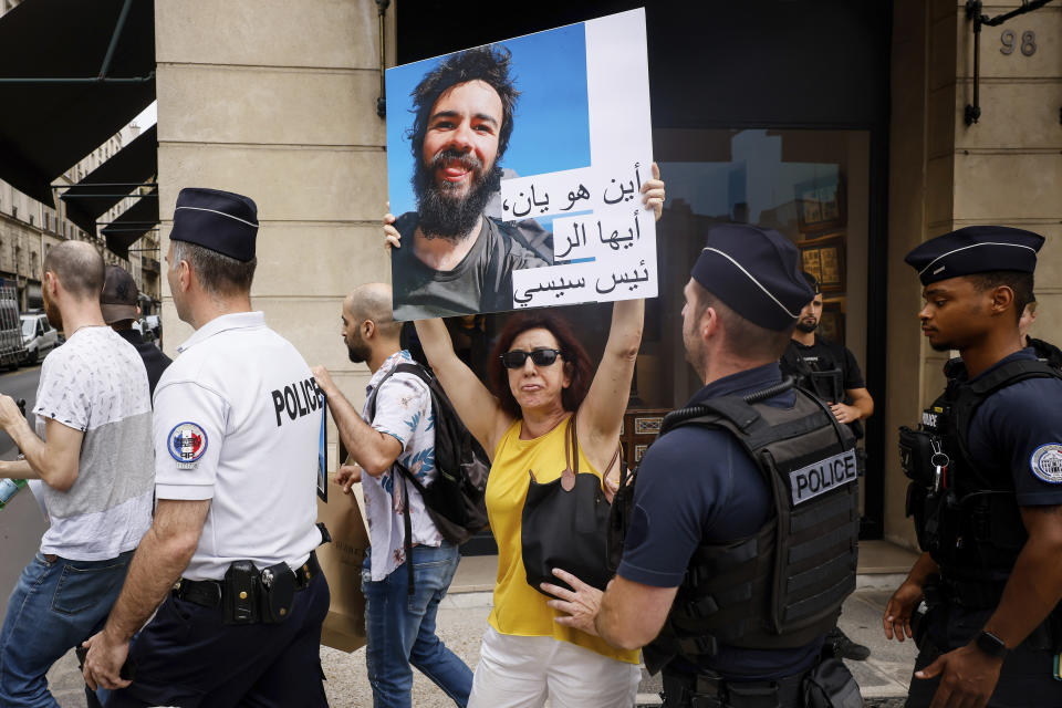 Police officers escort Isabel Leclercq, right, the mother of missing traveler Yann Bourdon in Egypt as she holds a picture of her son during during a march with relatives and friends near the Elysee Palace during Egyptian President Abdel Fattah el-Sissi visiting French President Emmanuel Macron in Paris, Friday, July 22. The family of a French backpacker who went missing in Egypt have used a visit to Paris by the Egyptian president to press for an investigation into his disappearance. (AP Photo/Thomas Padilla)