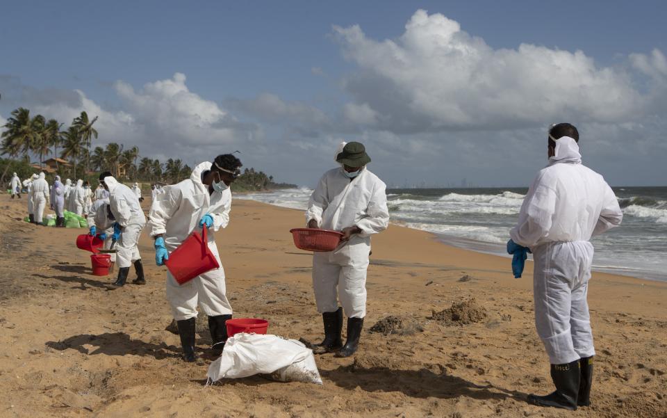 FILE - In this Friday, June 11, 2021, file photo, Sri Lankan navy soldiers collect plastic residue washed ashore from the fire damaged container ship MV X-Press Pearl at Kapungoda, on the outskirts of Colombo, Sri Lanka. Sri Lanka is seeking an interim claim of $40 million from the operator of a fire-ravaged cargo ship to cover the cost of fighting the blaze, officials said Saturday, June 12. (AP Photo/Eranga Jayawardena, File)