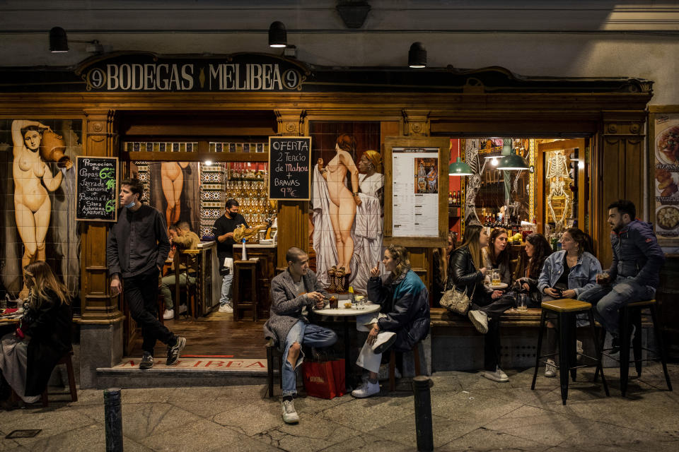 Tourists and locals have drinks at a bar in downtown Madrid, Spain, Friday, March 26, 2021. With its policy of open bars and restaurants, Madrid has built itself a reputation of something like Europe's last reduct for fun. That's driving some business to locals and giving politicians and the media much to debate about ahead of a regional election. (AP Photo/Bernat Armangue)