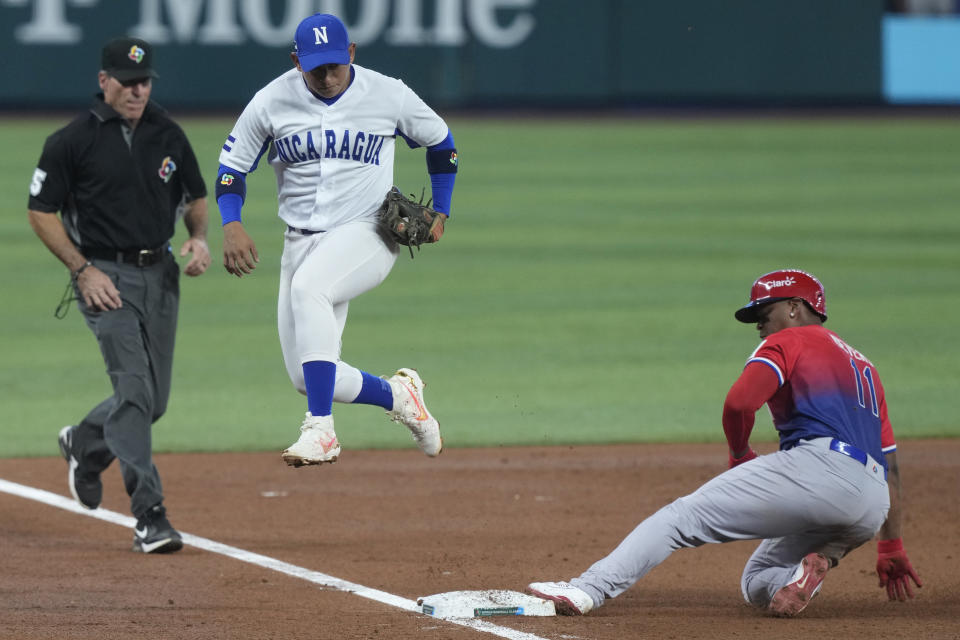 Nicaragua third baseman Benjamin Alegria (1) jumps out of the way after tagging Dominican Republic's Rafael Denvers (11) during the third inning of a World Baseball Classic game, Monday, March 13, 2023, in Miami. (AP Photo/Marta Lavandier)