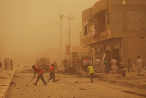 Enveloped by a sand storm, Iraqis clear the debris following two car bombs in the western city of Ramadi, in the Anbar province as a wave of bombings and shootings across the country killed at least 38 people and wounded dozens more