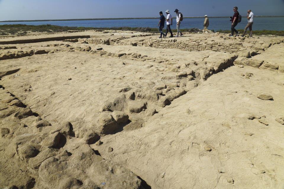 Archaeologists and journalists walk past uncovered ruins on Siniyah Island in Umm al-Quwain, United Arab Emirates, Monday, March 20, 2023. Archaeologists said Monday they have found the oldest pearling town in the Persian Gulf on an island off one of the northern sheikhdoms of the United Arab Emirates. (AP Photo/Jon Gambrell)