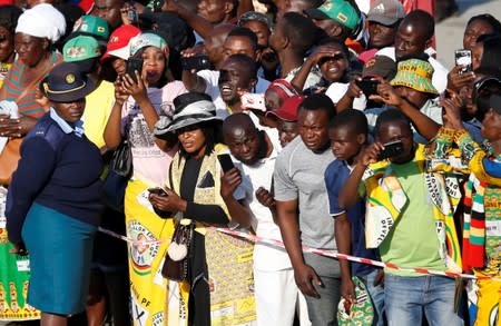 Zimbabweans look on as the body of former Zimbabwean President Robert Mugabe is transported to his home after arriving back in the country from Singapore, in Harare