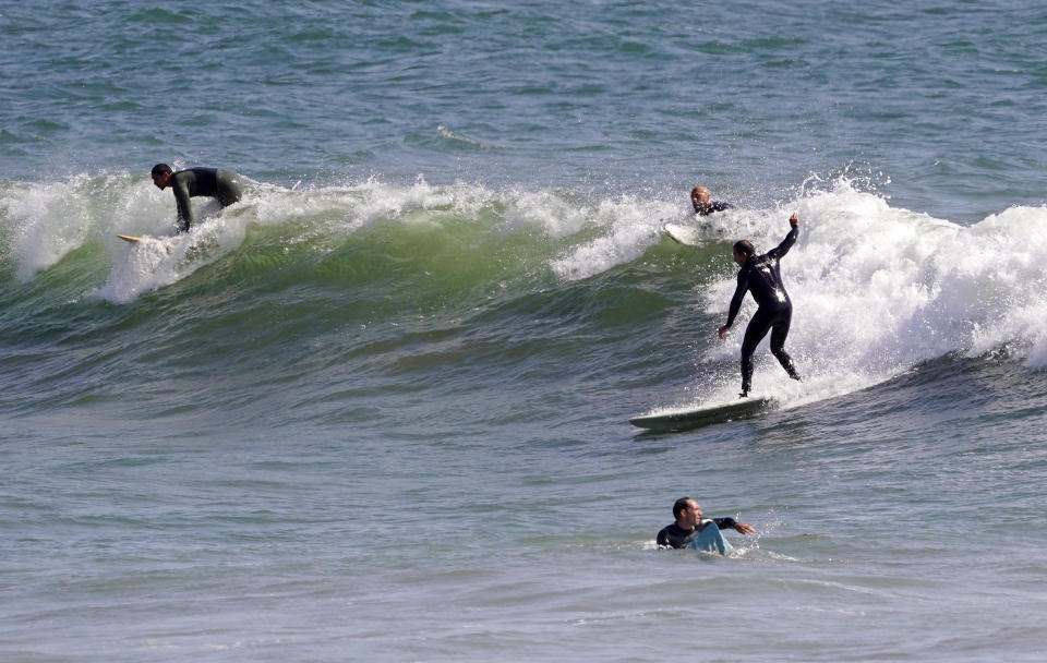 Surfers ride waves at County Line Beach during the coronavirus outbreak, Thursday, April 2, 2020, in Malibu, Calif. The new coronavirus causes mild or moderate symptoms for most people, but for some, especially older adults and people with existing health problems, it can cause more severe illness or death. (AP Photo/Mark J. Terrill)