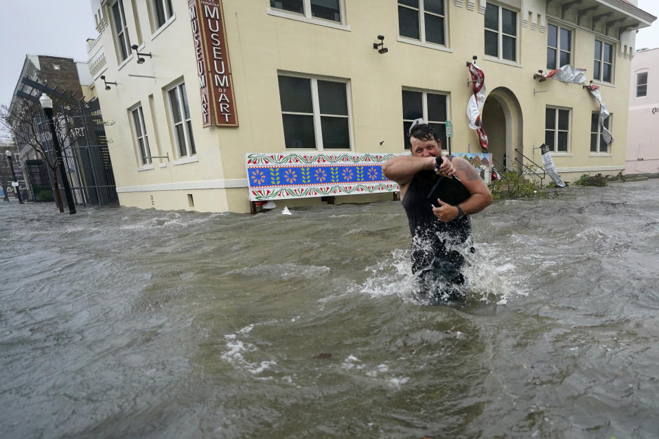 Trent Airhart wades through floodwaters, Wednesday, Sept. 16, 2020, in downtown Pensacola, Fla. Hurricane Sally made landfall Wednesday near Gulf Shores, Alabama, as a Category 2 storm, pushing a surge of ocean water onto the coast and dumping torrential rain that forecasters said would cause dangerous flooding from the Florida Panhandle to Mississippi and well inland in the days ahead.(AP Photo/Gerald Herbert)