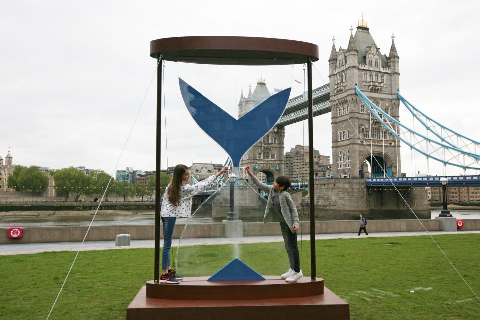 <p>Amelia, aged 9, and Joshua, aged 6, interact with a 3.5 metre hourglass in Potter's Field, London, by clean water charity WaterAid ahead of the G7 leaders' summit in June that illustrates the urgency of the climate crisis that is leading to more people being forced into water scarcity. Picture date: Tuesday May 25, 2021.</p>
