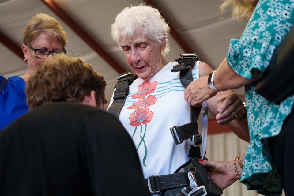 Marg Burg looks down as instructor Collin Lyons helps her put on a harness to prepare to skydive on Burg's 90th birthday at Skydive Buckeye on July 20, 2023 in Buckeye, Arizona.