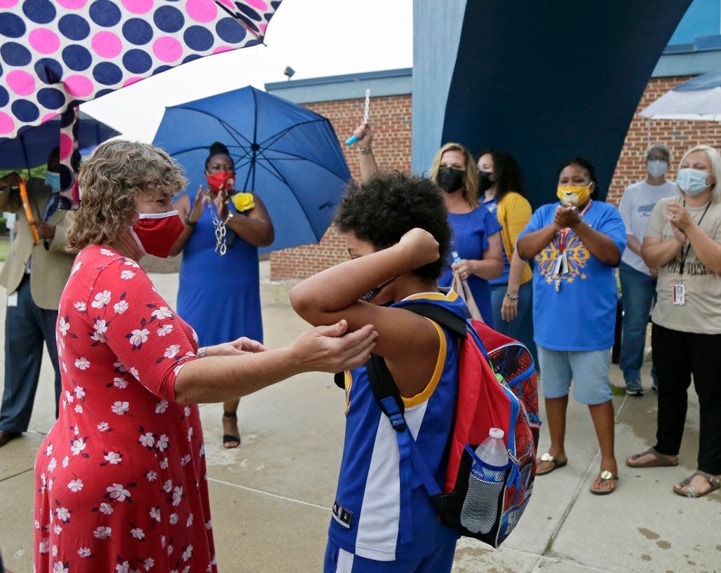 School nurse Deb Strouse, left, helps fourth grade student Isaiah Coleman, adjust his mask on the first day of school on July 29, 2021, for Woodcrest Elementary, Columbus City Schools' only year-round program.