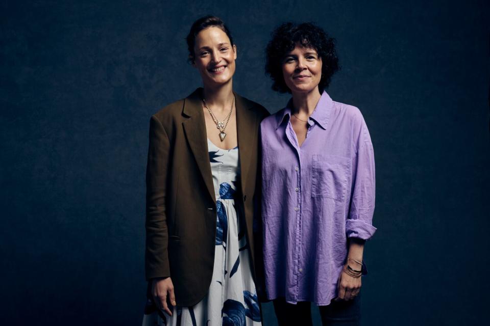 Two smiling women stand together.