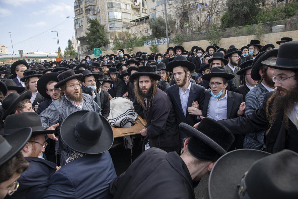 Ultra-Orthodox Jews carry the body of prominent rabbi Meshulam Soloveitchik during his funeral in Jerusalem, Sunday, Jan. 31, 2021. The mass ceremony took place despite the country's health regulations banning large public gatherings, during a nationwide lockdown to curb the spread of the virus. (AP Photo/Ariel Schalit)