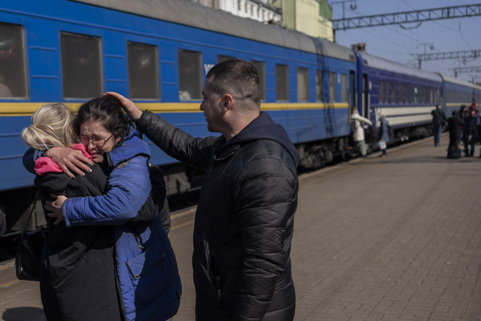 Olga Nikitina, center, who escaped the besieged city of Mariupol embraces her sister after arriving in Lviv, western Ukraine on Sunday, March 20, 2022. (AP Photo/Bernat Armangue)