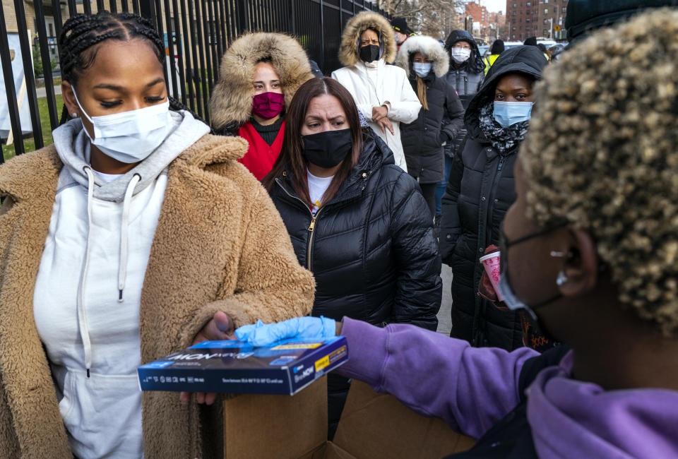 FILE - People line up and receive test kits to detect COVID-19 as they are distributed in New York on Dec. 23, 2021. The COVID-19 surge caused by the omicron variant means once-reliable indicators of the pandemic's progress are much less so, complicating how the media is able to tell the story. (AP Photo/Craig Ruttle, File)