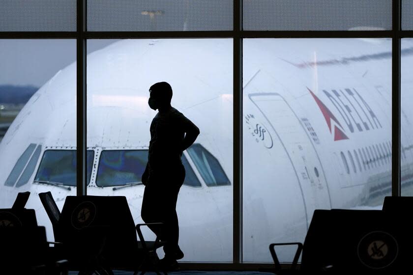 A passenger wears a face mask to help prevent the spread of the new coronavirus as he waits for a Delta Airlines flight at Hartsfield-Jackson International Airport in Atlanta, Thursday, Feb. 18, 2021. (AP Photo/Charlie Riedel)