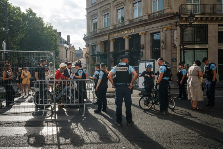 Agentes de la Gendarmería francesa comprueban los códigos QR y los equipajes de peatones y ciclistas en un puesto de control de barreras para circular cerca del Louvre en París el 18 de julio de 2024 (Dimitar DILKOFF)