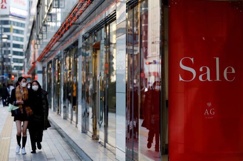 FILE PHOTO: Women wearing protective masks walk in a shopping district in Tokyo