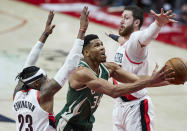 Milwaukee Bucks forward Giannis Antetokounmpo, center, shoots between Portland Trail Blazers forward Robert Covington, left, and center Jusuf Nurkic during the second half of an NBA basketball game in Portland, Ore., Friday, April 2, 2021. (AP Photo/Craig Mitchelldyer)