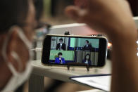 A mobile phone shows the live streaming of candidates for the presidential election of the ruling Liberal Democratic Party speaking at the debate session held by Japan National Press club Saturday, Sept. 18, 2021 in Tokyo. The contenders are, clockwise from top left, Taro Kono, the cabinet minister in charge of vaccinations, Fumio Kishida, former foreign minister, Seiko Noda, former internal affairs minister, and Sanae Takaichi, former internal affairs minister. (AP Photo/Eugene Hoshiko, Pool)