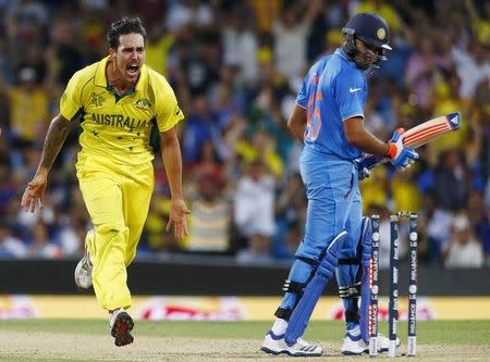 Australian bowler Mitchell Johnson (L) reacts after bowling out India's Rohit Sharma (R) during their Cricket World Cup semi-final match in Sydney, March 26, 2015. REUTERS/David Gray