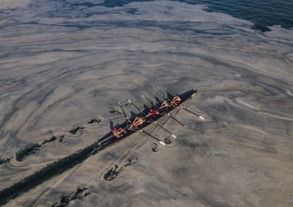 People ride a canoe through "sea snot" in Turkey's Marmara Sea by the Caddebostan shore, on the Asian side of Istanbul, Tuesday, June 8, 2021. Sea snot is a huge mass of marine mucilage, a thick, slimy substance made up of compounds released by marine organisms. (AP Photo/Kemal Aslan)