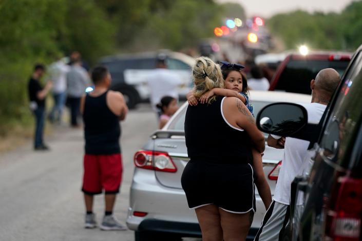 Onlookers stand near the scene where a tractor-trailer with multiple dead bodies was discovered, Monday, June 27, 2022, in San Antonio.