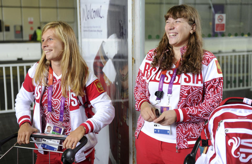 Tatiana Bazyuk (L) and Svetlana Shnitko part of the Russian Olympic sailing squad smile as they wait to board a bus after arriving at Heathrow airport, London, July 16, 2012. The Lndon 2012 Olympic Games start in 11 days time. REUTERS/Paul Hackett (BRITAIN - Tags: SPORT OLYMPICS)