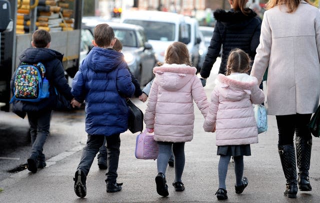 File photo dated 13/07/22 of parents walking their children to school. 