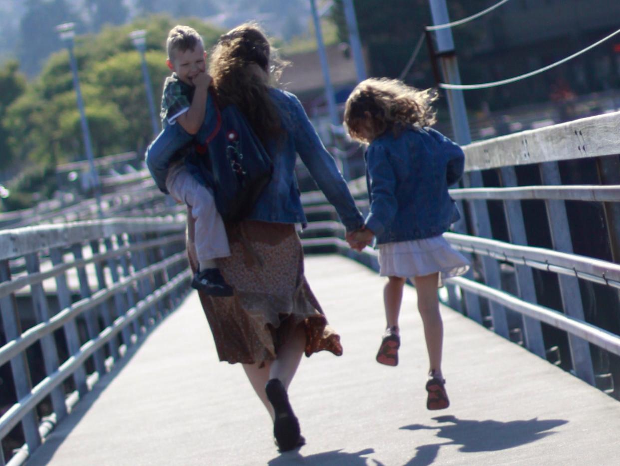 Angie Ebba and her two children walking down a boardwalk
