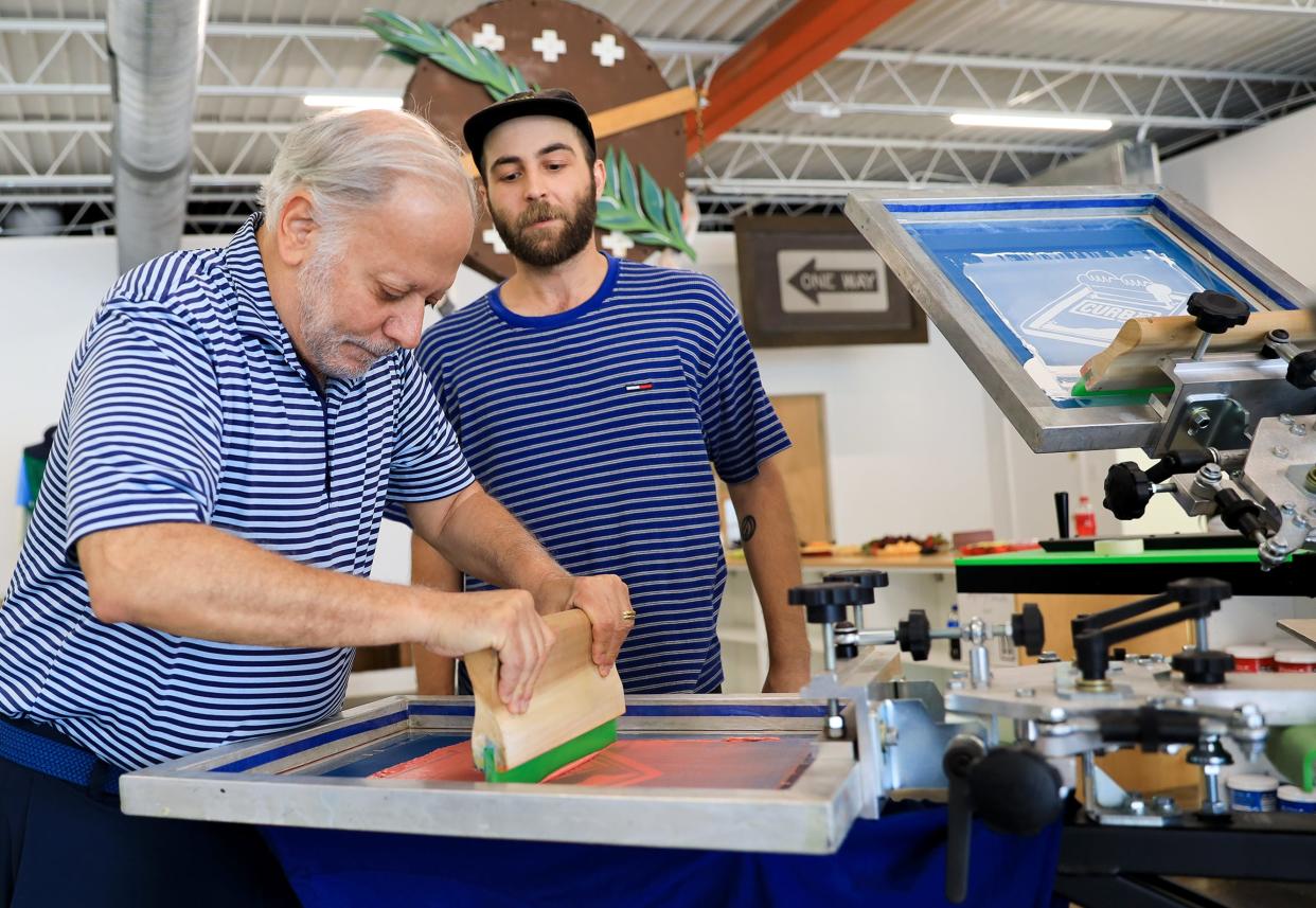 Mike Joseph, former Homeless Alliance board member, gets help screen printing a T-shirt from Jacob Danley, assistant manager of Curbside Apparel, during the apparel company's recent grand opening at 1106 NW 6.