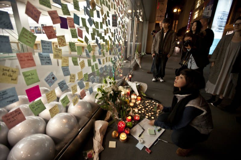 People gather at an Apple store in San Francisco to leave flowers, candles and cover the glass with notes after learning about the death of Apple founder Steve Jobs on October 5, 2011. File Photo by Terry Schmitt/UPI