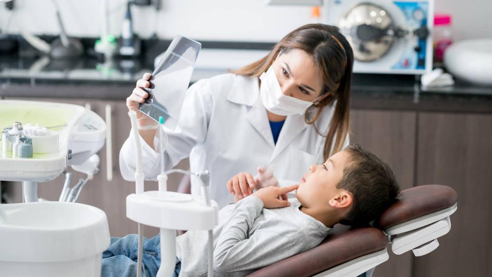 Happy dentist looking at an x-ray with his young patient at the office - healthcare and medicine concepts.