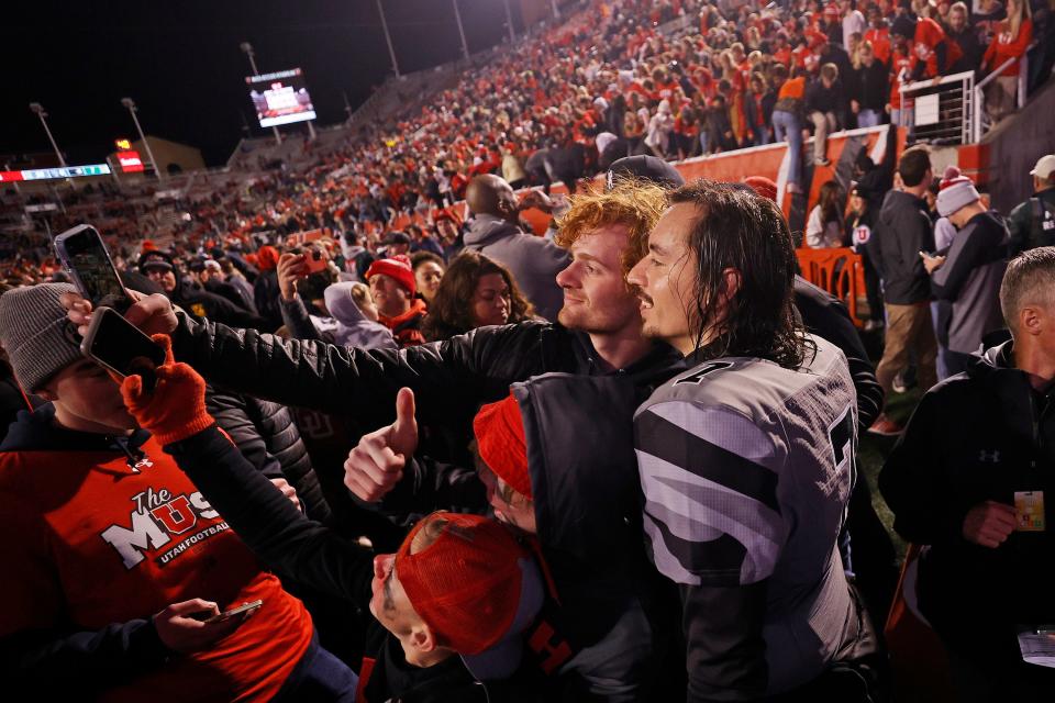 A fan takes a selfie with Utah quarterback Cameron Rising while they celebrate their win against the Oregon Ducks at Rice-Eccles Stadium in Salt Lake City on Nov. 20