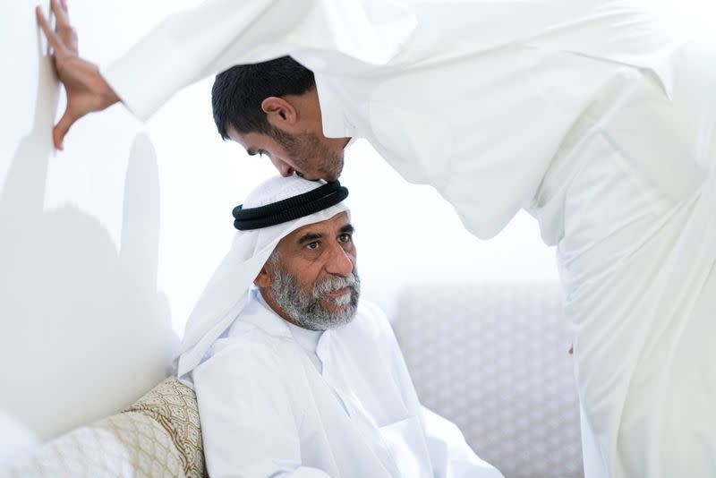 Ahmad al-Enezi, a stateless frontline worker, kisses his father's head at their home in Sulaibiya