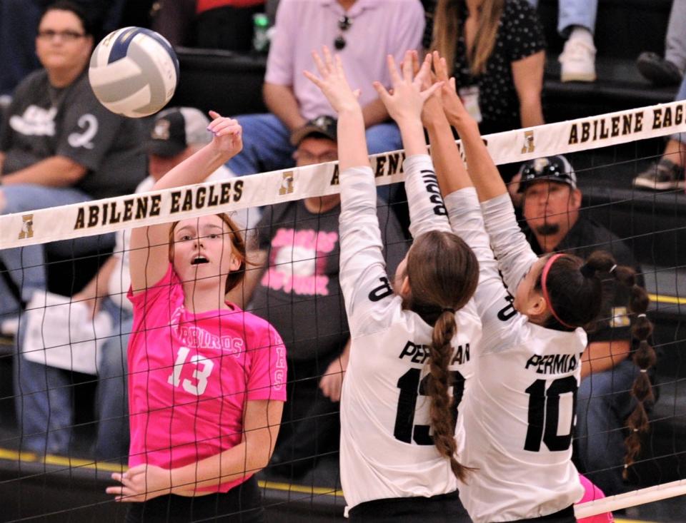 Abilene High's Ryleigh Lawson, left, hits around Odessa Permian's Riley Nichols, center, and Nyxalee Munoz on Oct. 19 at Eagle Gym.