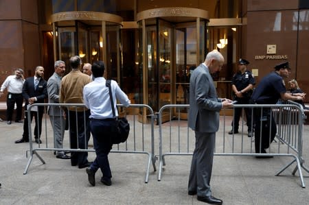 Workers wait to enter 787 7th Avenue one day after a helicopter crashed on the building's roof in New York