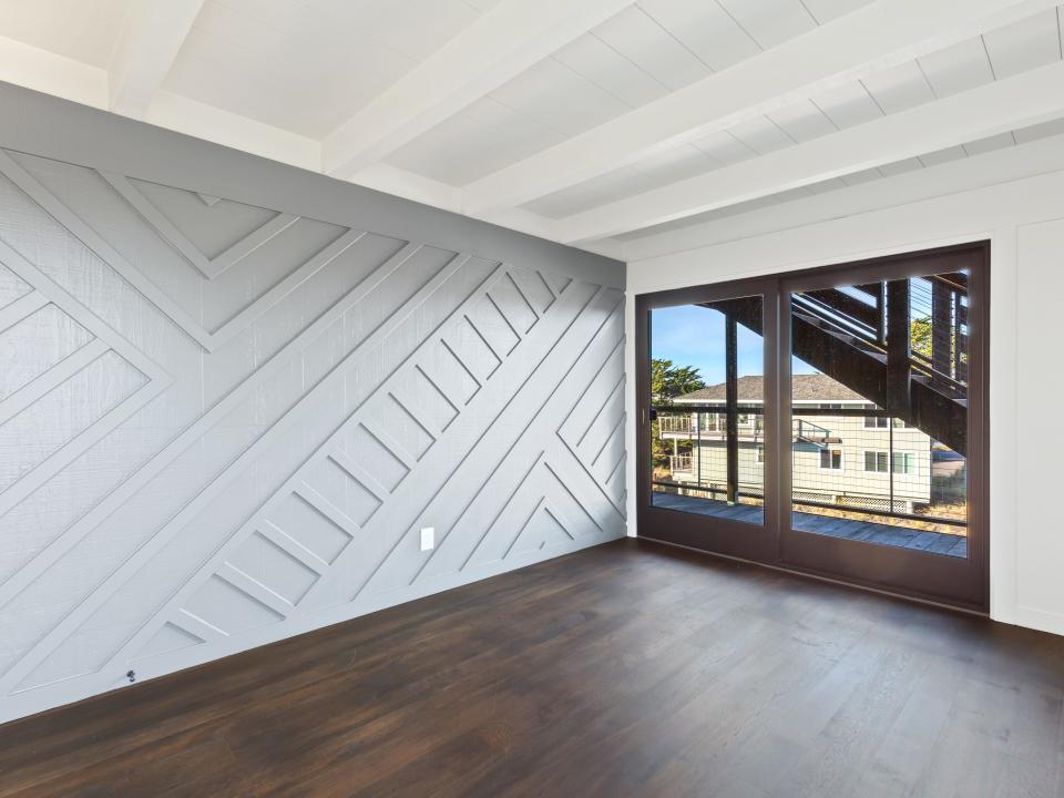 A light-gray wooden accent wall in a room with dark wood floors