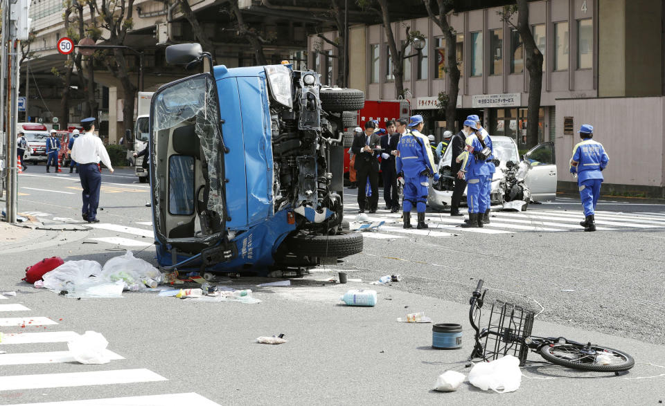 Police officers inspect the scene of a car accident in Tokyo Friday, April 19, 2019. A car, right rear, driven by an 87-year-old man crashed into a garbage truck, foreground, on a Tokyo street Friday, killing a woman and a girl who were on a bicycle, according to police. (Shinji Kita/Kyodo News via AP)